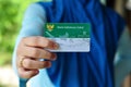 A young mother holds a Healthy Indonesia Card Health Insurance card from the Government of Indonesia