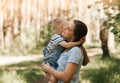 A young mother holds in her arms and hugs a little boy in the summer in nature Royalty Free Stock Photo