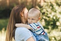 A young mother holds in her arms and hugs a little boy in the summer in nature Royalty Free Stock Photo