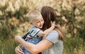 A young mother holds in her arms and hugs a little boy in the summer in nature Royalty Free Stock Photo