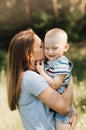 A young mother holds in her arms and hugs a little boy in the summer in nature Royalty Free Stock Photo