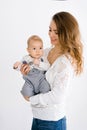 A young mother holds her little son in her arms and smiles on a white background Royalty Free Stock Photo