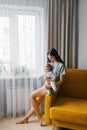 Young mother holds her newborn baby in her arms. A woman and a newborn girl are resting in the living room. Family at home Royalty Free Stock Photo