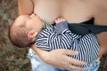 Young mother breastfeed newborn baby on walk. Close up.