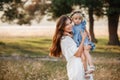 Young mother hugging her little daughter in the park on summer day. Family holiday in garden. Portrait mom with child Royalty Free Stock Photo