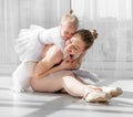 Young mother hugging little smiling daughter in ballet studio