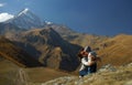 Young mother hugging small child on background of snowy glacier and brown mountains at autumn time. Travelling with kids