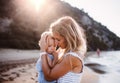 Young mother with a toddler girl on beach on summer holiday at sunset. Royalty Free Stock Photo