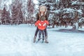 Young mother insures supports child children`s skis, little boy son 4 years. Winter forest park, background snow drifts