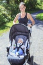 Young mother jogging with a baby buggy Royalty Free Stock Photo