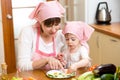 Young mother and kid making funny vegetables dish