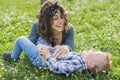 Young mother and kid relaxing outdoor laying down on grass in a park garden. mom and child having fun chilling outside in the Royalty Free Stock Photo