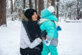 Young mother kisses her baby in the winter park Royalty Free Stock Photo