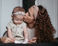 Young mother kisses sad baby girl Royalty Free Stock Photo