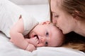 Young mother kissing baby lying on bed, close up. Lovely time together. Happy motherhood concept Royalty Free Stock Photo