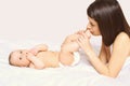 Young mother kissing baby lying on the bed Royalty Free Stock Photo