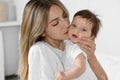 Young mother kissing cute little baby indoors Royalty Free Stock Photo