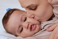 Young mother, kissing her baby boy at home. Family concept. Closeup portrait of loving mother young woman kissing little Royalty Free Stock Photo