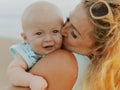 Young mother kissing her baby son. Mum with infant spending time on the beach. Smiling infant boy. Summer vacation in Asia. Family Royalty Free Stock Photo