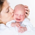 Young mother kissing her crying newborn baby Royalty Free Stock Photo