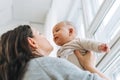 Young mother kissing her cute baby boy on hands in bright room love emotion Royalty Free Stock Photo