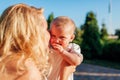 Young mother kissing and hugging baby girl in summer park. Family having fun outdoors Royalty Free Stock Photo