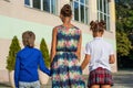 Young mother leads her daughter and son to school.