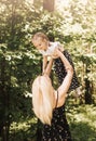 A young mother lifts up in her arms a little daughter in the park in the summer. Mom and child in nature Royalty Free Stock Photo