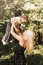 A young mother lifts up in her arms a little daughter in the park in the summer. Mom and child in nature Royalty Free Stock Photo