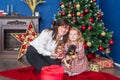 Young mother with litle cute daughter and little puppies of dachshund sitting near near Christmas tree