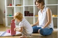 Young mother and little baby assembling pink cube Maria Montessori ecological materials