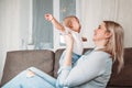 Young mother with little baby daughter on sofa at home the baby crying mom soothes Royalty Free Stock Photo