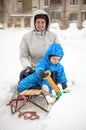 Young mother and little boy enjoying sleigh ride. Child sledding. Toddler kid riding sledge. Children play outdoors in snow. Kids Royalty Free Stock Photo