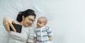 Young mother and little cute baby boy lying on bed taking selfie photos with mobile phone at home together. Asian Mom and son Royalty Free Stock Photo