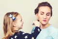 Young mother and little daughter while applying makeup. Beauty and fashion. Mom and child girl celebrate mother`s day. Cute littl Royalty Free Stock Photo