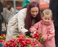Young mother with little daughter buying fresh radishes
