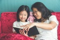 Young mother and little daughter girl reading a book on sofa at Royalty Free Stock Photo