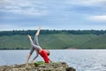 Young mother and little daughter practicing balancing yoga pose on the rock near river. Royalty Free Stock Photo