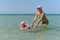 A young mother with a little daughter swim in the sea.