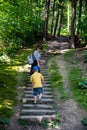 young mother with little kid climbing up by old stairs in forest Royalty Free Stock Photo