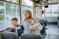 Young mother with little kids travelling in tram in summer, commuting and sustainable lifestyle concept.