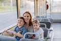 Young mother with little kids travelling in tram in summer, commuting and sustainable lifestyle concept.