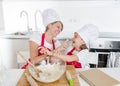 Young mother and little sweet daughter in cook hat and apron cooking together baking at home kitchen Royalty Free Stock Photo