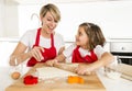 Young mother and little sweet daughter cooking in kitchen preparing desert with rolling pin rod Royalty Free Stock Photo