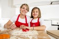 Young mother and little sweet daughter cooking in kitchen preparing desert with rolling pin rod Royalty Free Stock Photo