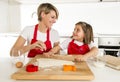 Young mother and little sweet daughter cooking in kitchen preparing desert with rolling pin rod Royalty Free Stock Photo