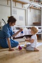 Young mother and little toddler playing childish colorful hand bells music sound at home