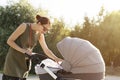 Young mother looking into baby carriage in park. Mother strolling with newborn