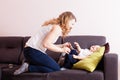 Young mother loughing tickling her adorable toddler son on their couch.