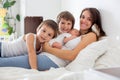 Young mother lying in bed with her newborn baby boy and his older brothers Royalty Free Stock Photo